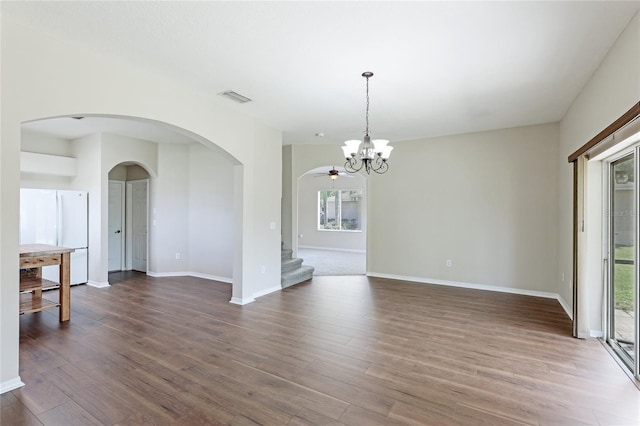 unfurnished dining area featuring arched walkways, plenty of natural light, stairway, and wood finished floors