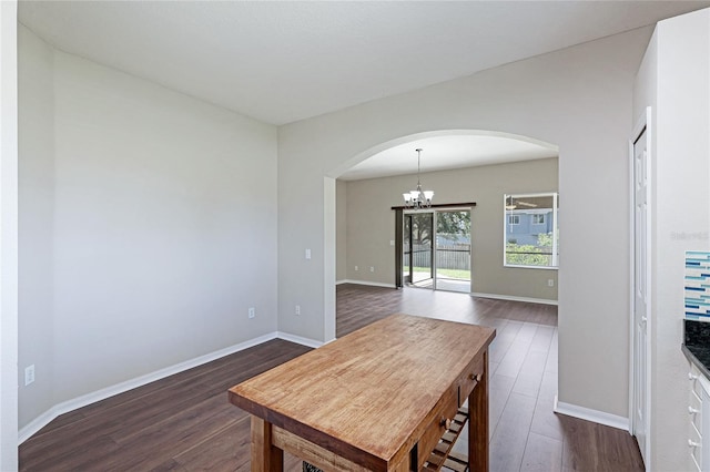 dining room with arched walkways, a chandelier, dark wood-style flooring, and baseboards