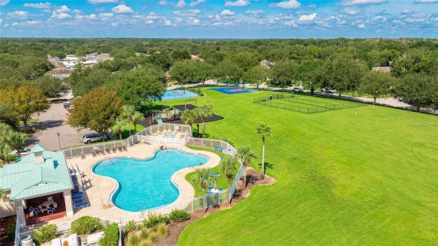 drone / aerial view of a pool area and a heavily wooded area