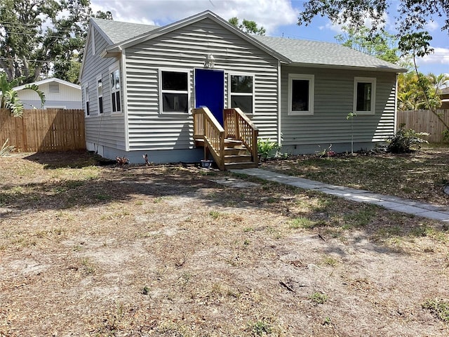 bungalow-style home with fence and roof with shingles
