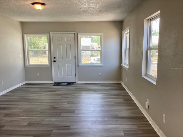 entrance foyer featuring dark wood-type flooring, a textured ceiling, and baseboards