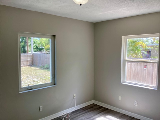 empty room featuring baseboards, wood finished floors, and a textured ceiling