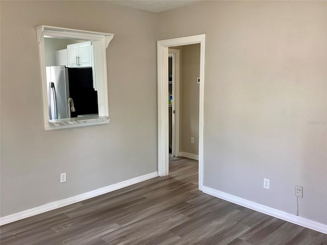 spare room with dark wood-type flooring and baseboards