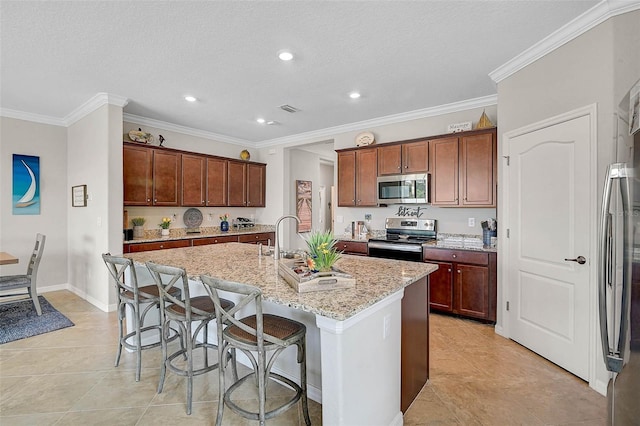 20542 Trattoria Loop, Venice, FL 34293 - kitchen featuring appliances with stainless steel finishes, light tile patterned flooring, a center island with sink, light stone counters, and crown molding