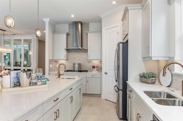 kitchen with wall chimney exhaust hood, a sink, appliances with stainless steel finishes, decorative backsplash, and ornamental molding