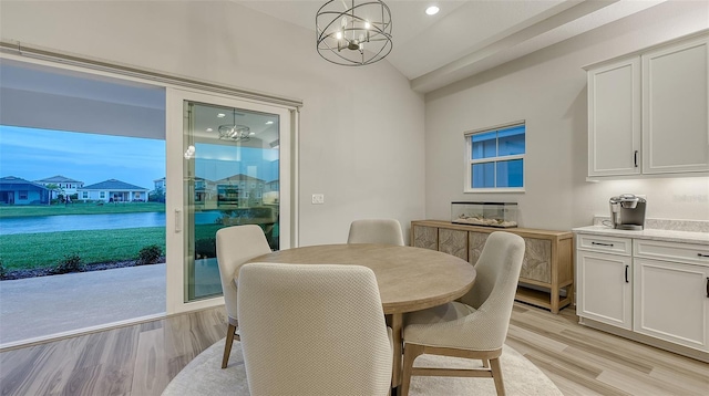 dining area with vaulted ceiling, light wood finished floors, a chandelier, a water view, and recessed lighting