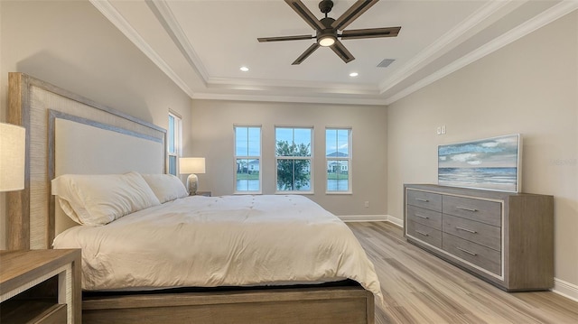 bedroom with light wood-type flooring, a raised ceiling, baseboards, crown molding, and a ceiling fan