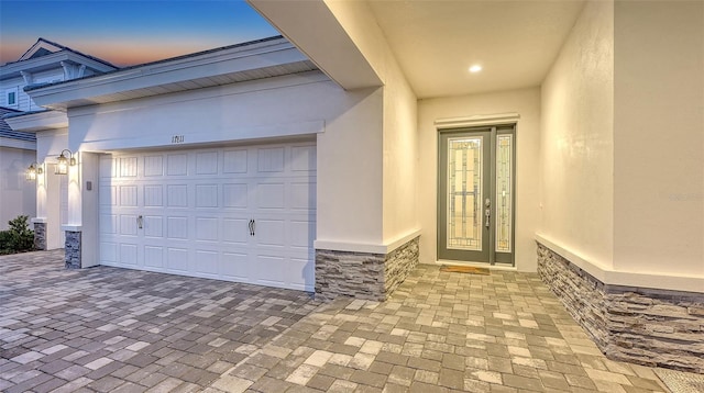entrance to property with driveway and an attached garage
