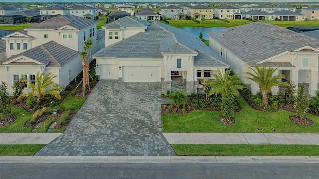 view of front of home featuring a residential view, a garage, decorative driveway, stucco siding, and stone siding