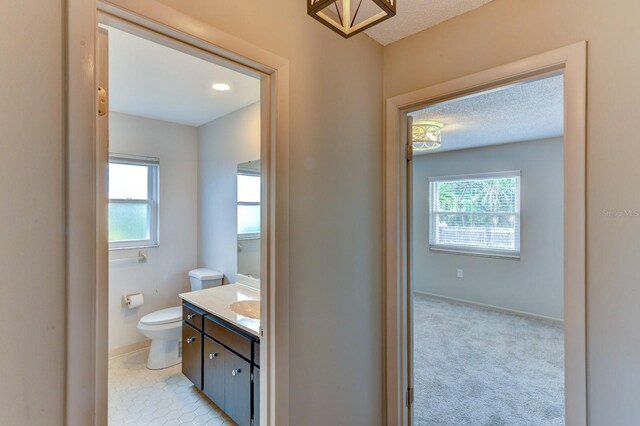 7719 9th Avenue Dr NW, Bradenton, FL 34209 - bathroom featuring toilet, vanity, healthy amount of natural light, a textured ceiling, and baseboards