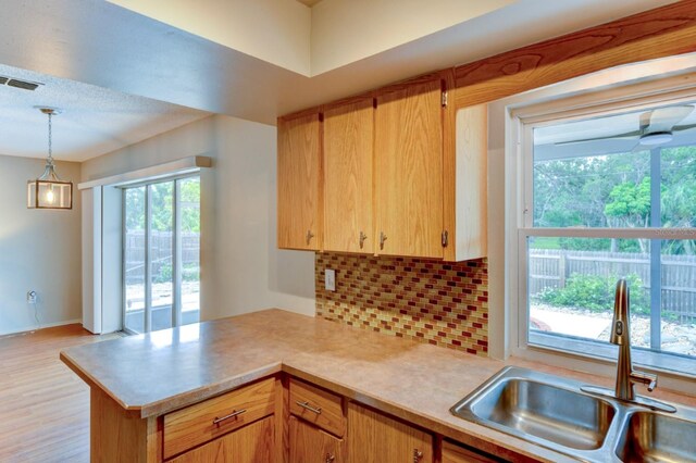 7719 9th Avenue Dr NW, Bradenton, FL 34209 - kitchen with a sink, light countertops, a peninsula, backsplash, and decorative light fixtures