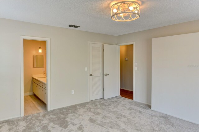 7719 9th Avenue Dr NW, Bradenton, FL 34209 - unfurnished bedroom featuring light colored carpet, a chandelier, ensuite bath, a sink, and a textured ceiling