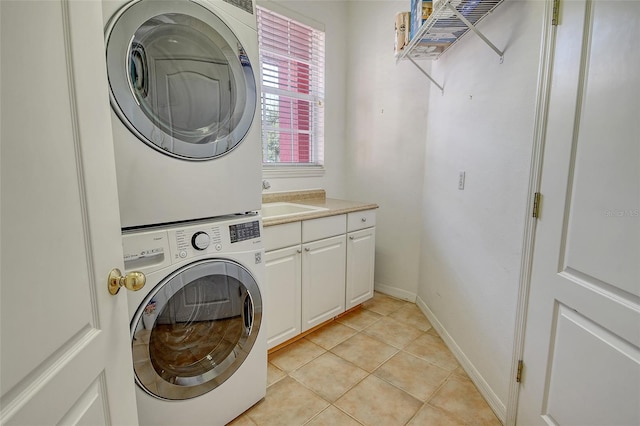 4322 Reflections Pkwy, Sarasota, FL 34233 - laundry area featuring stacked washer / drying machine, cabinet space, light tile patterned floors, and baseboards