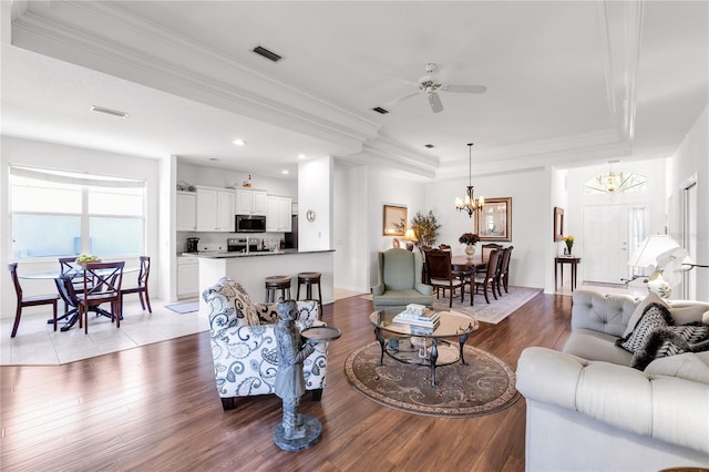315 Heritage Isles Way, Bradenton, FL 34212 - living area featuring a raised ceiling, a chandelier, wood finished floors, crown molding, and a ceiling fan