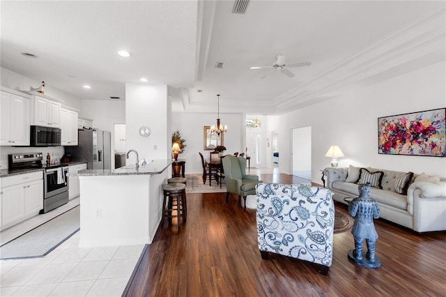 315 Heritage Isles Way, Bradenton, FL 34212 - living room featuring a tray ceiling, a ceiling fan, recessed lighting, a chandelier, and ornamental molding