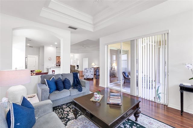 315 Heritage Isles Way, Bradenton, FL 34212 - living room featuring wood finished floors, ornamental molding, arched walkways, a tray ceiling, and baseboards