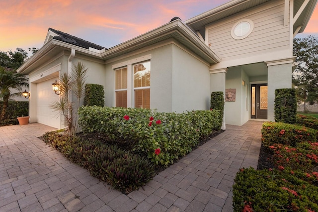 view of front of house featuring stucco siding, a garage, and driveway