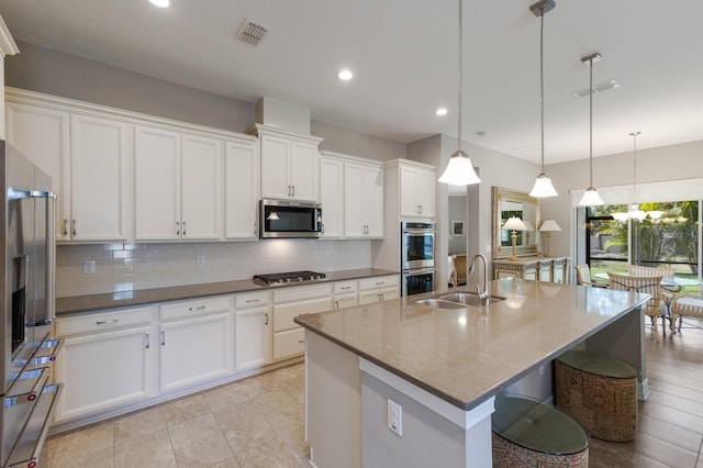 kitchen with a sink, stainless steel appliances, backsplash, white cabinets, and recessed lighting