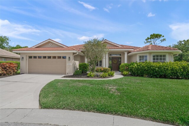 6664 Deering Cir, Sarasota, FL 34240 - mediterranean / spanish house featuring stucco siding, an attached garage, a front lawn, and a tiled roof