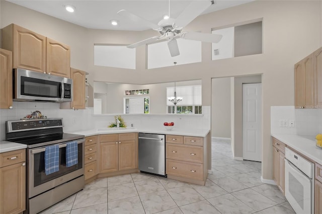 6664 Deering Cir, Sarasota, FL 34240 - kitchen featuring stainless steel appliances, light brown cabinets, a high ceiling, tasteful backsplash, and light countertops