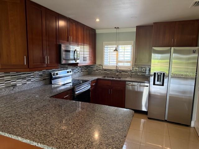 2616 Hidden Lake Dr N Unit A, Sarasota, FL 34237 - kitchen featuring appliances with stainless steel finishes, dark stone countertops, a peninsula, tasteful backsplash, and ornamental molding