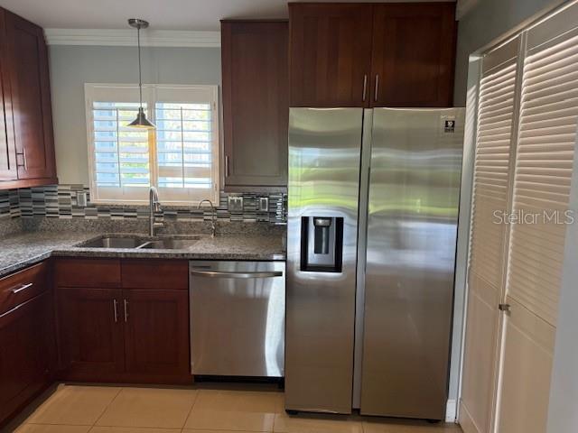 2616 Hidden Lake Dr N Unit A, Sarasota, FL 34237 - kitchen with stainless steel appliances, tasteful backsplash, dark stone counters, light tile patterned floors, and crown molding