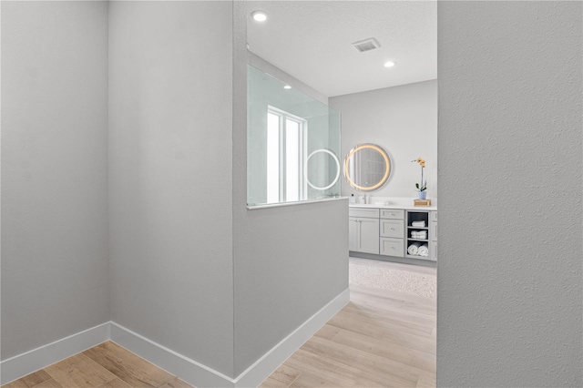 5910 Red Mangrove Ln, Bradenton, FL 34210 - hall featuring light wood-style flooring, a textured wall, baseboards, and recessed lighting