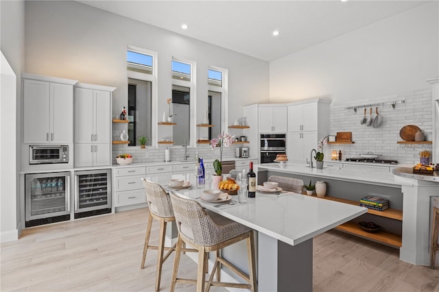 5910 Red Mangrove Ln, Bradenton, FL 34210 - kitchen with open shelves, decorative backsplash, beverage cooler, a breakfast bar area, and a towering ceiling