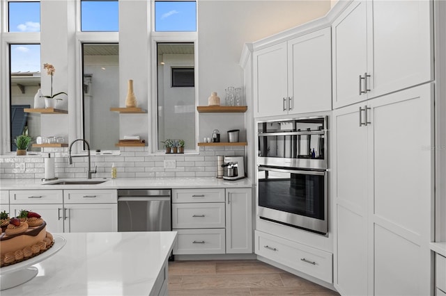 5910 Red Mangrove Ln, Bradenton, FL 34210 - kitchen with open shelves, a sink, stainless steel appliances, tasteful backsplash, and white cabinetry