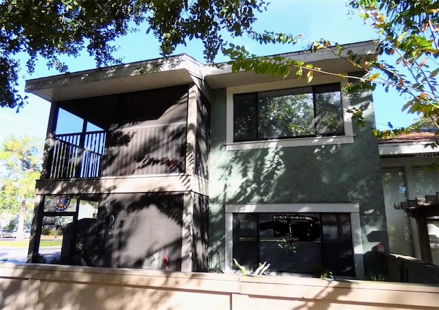 rear view of house featuring a balcony and stucco siding