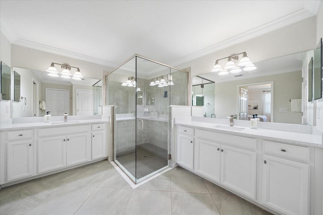 bathroom with a shower stall, ornamental molding, tile patterned flooring, a chandelier, and two vanities