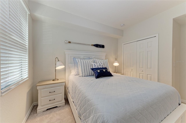bedroom with light colored carpet, a closet, and baseboards