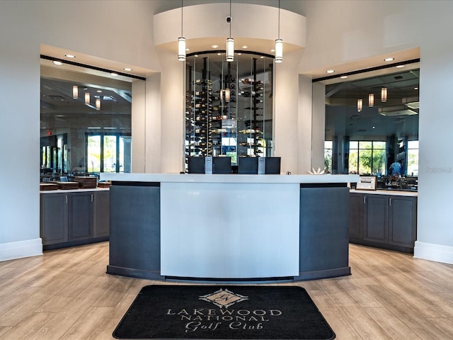 bar area featuring light wood-style floors, hanging light fixtures, baseboards, and recessed lighting