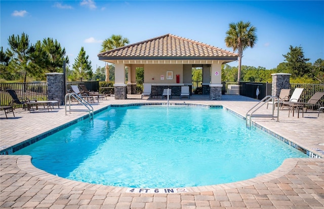 community pool with fence, a patio area, and a gazebo