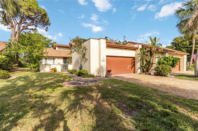 mid-century home featuring stucco siding, driveway, a front lawn, and an attached garage