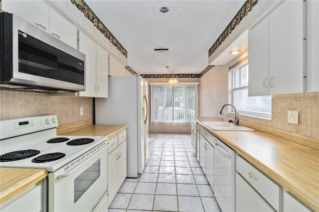 kitchen with white appliances, a sink, a textured ceiling, light countertops, and backsplash