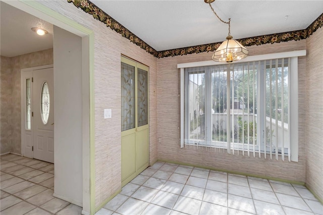unfurnished dining area featuring light tile patterned floors, a chandelier, and baseboards
