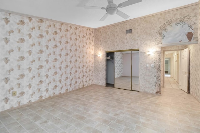 unfurnished bedroom featuring wallpapered walls, a closet, crown molding, and ceiling fan