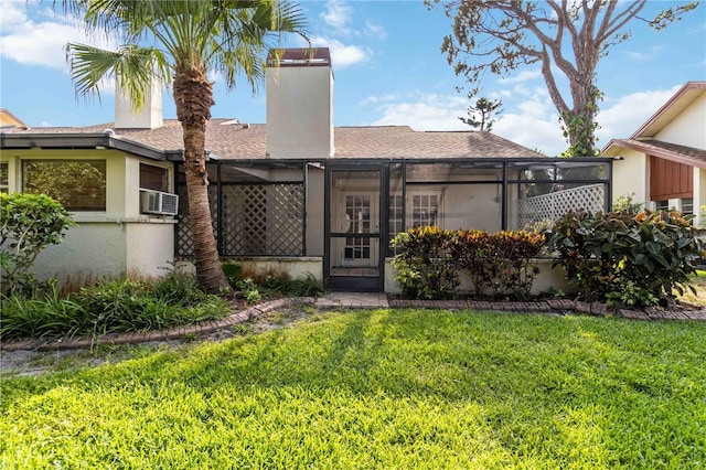 ranch-style home featuring roof with shingles, a chimney, a front lawn, glass enclosure, and stucco siding