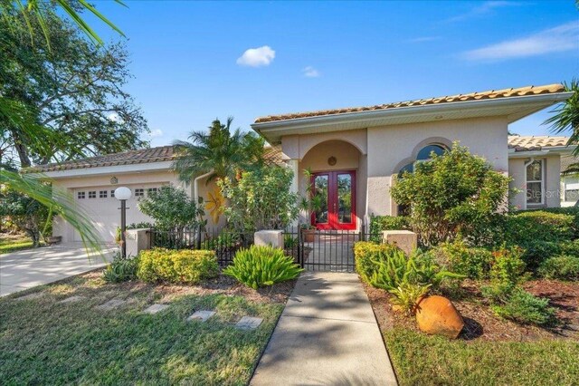 4978 Cedar Oak Way, Sarasota, FL 34233 - mediterranean / spanish house with a garage, stucco siding, a tile roof, concrete driveway, and french doors