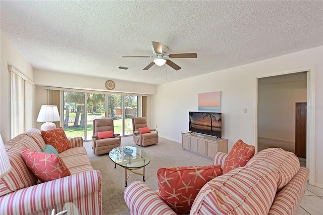 living area with ceiling fan, a textured ceiling, and light colored carpet
