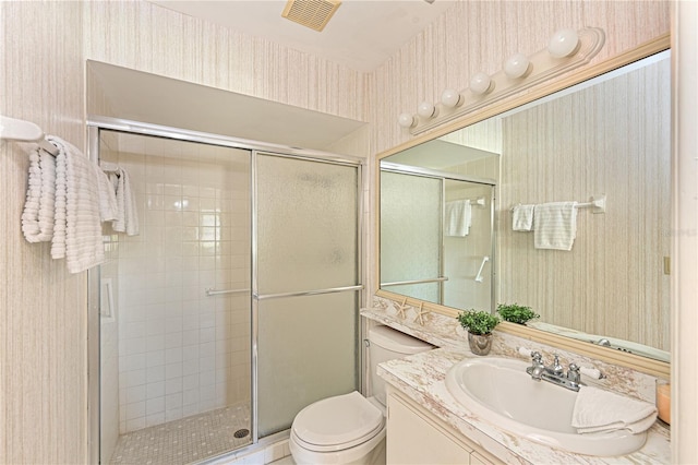 full bathroom featuring a stall shower, vanity, toilet, and wallpapered walls