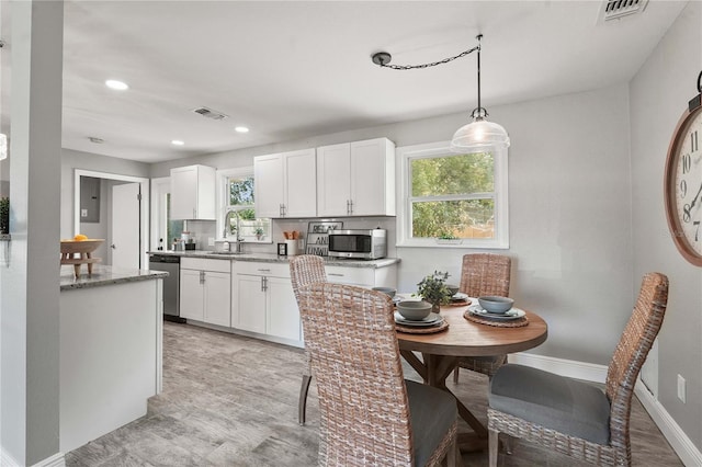 3102 16th Ave W, Bradenton, FL 34205 - kitchen with stainless steel appliances, white cabinetry, a sink, light stone counters, and recessed lighting