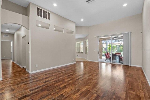 7626 Double Pine Dr, Sarasota, FL 34240 - unfurnished living room with dark wood-style floors, arched walkways, baseboards, and recessed lighting