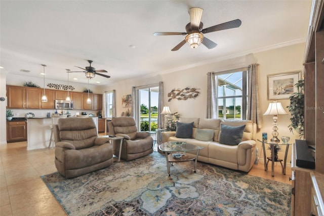 living room with a ceiling fan, ornamental molding, and light tile patterned flooring