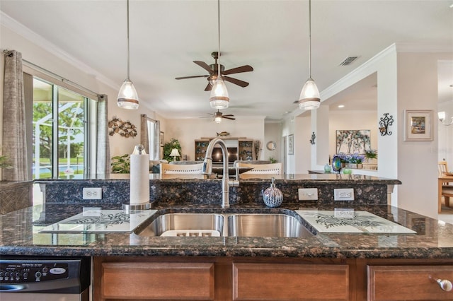 kitchen with brown cabinets, a ceiling fan, ornamental molding, dark stone counters, and a sink