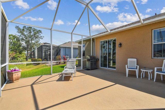 view of patio featuring glass enclosure and a grill