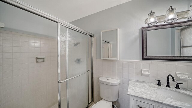 5706 10th Avenue Dr W, Bradenton, FL 34209 - bathroom with vanity, a shower stall, toilet, and tile walls