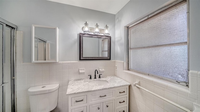 5706 10th Avenue Dr W, Bradenton, FL 34209 - bathroom with tile walls, vanity, toilet, wainscoting, and a shower with shower door
