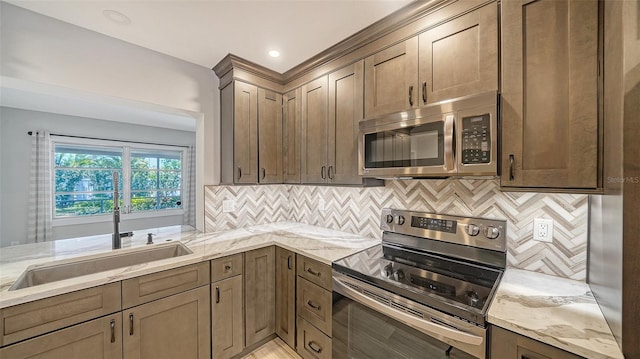 5706 10th Avenue Dr W, Bradenton, FL 34209 - kitchen featuring appliances with stainless steel finishes, a sink, light stone countertops, and backsplash